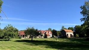 Uma propriedade rural com um extenso gramado, um celeiro e uma casa com telhado vermelho.