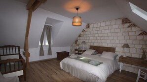 Quarto com teto inclinado, cama de madeira, mesa de cabeceira, abajur e janela com cortinas.
