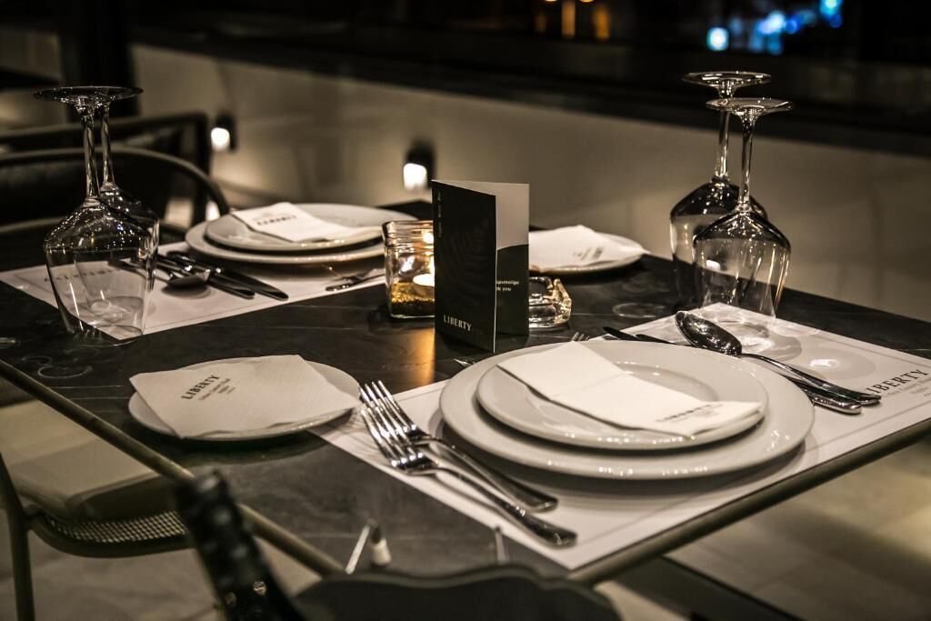 A table set for two with a menu, glasses, and cutlery.
