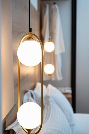 A modern hotel room with a bed, a wooden headboard, and a hanging pendant light fixture. - Liberty Hotel of Nafplio (Nafplio)