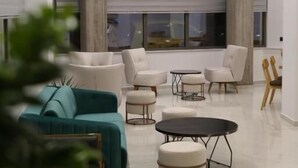 A modern living room with a teal sofa, white armchairs, and a round coffee table. - Liberty Hotel of Nafplio (Nafplio)