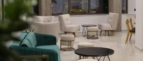 Una sala de estar moderna con un sofá color turquesa, sillones blancos y una mesa de centro redonda.