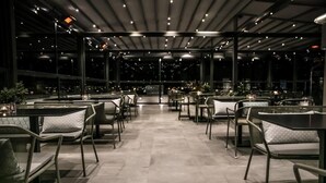 An indoor dining area with tables and chairs arranged in rows, large windows, and a modern ceiling design. - Liberty Hotel of Nafplio (Nafplio)