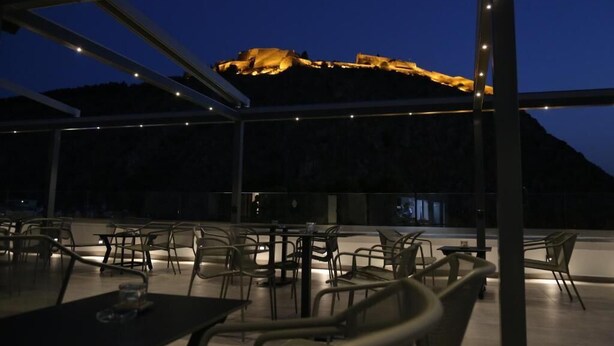 An outdoor dining area with tables and chairs, overlooking a mountainous landscape at dusk. - Liberty Hotel of Nafplio (Nafplio)