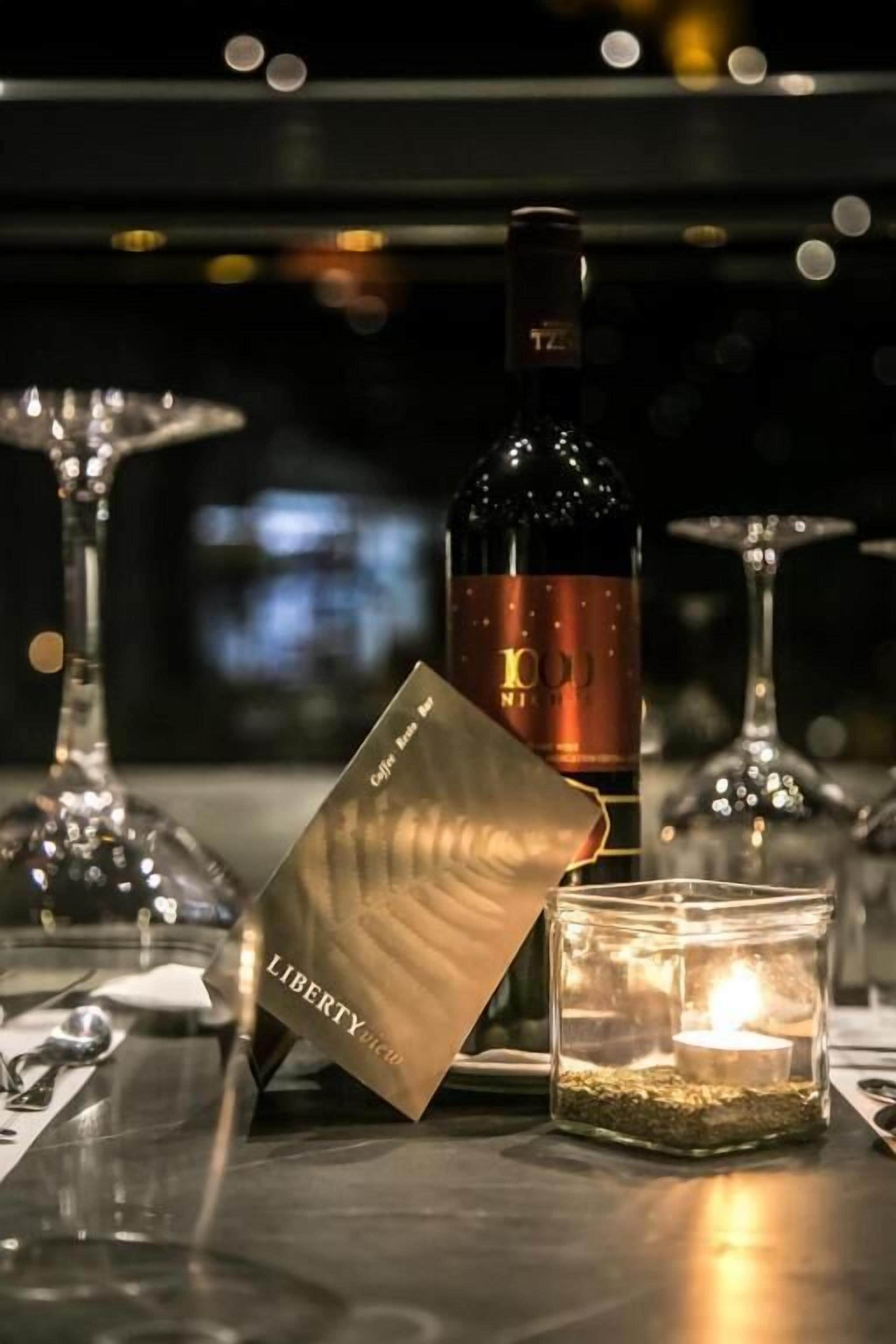 Una botella de vino, una vela y una tarjeta sobre una mesa.