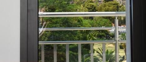 A view from a balcony with a railing, overlooking a rocky hill with a fort-like structure.