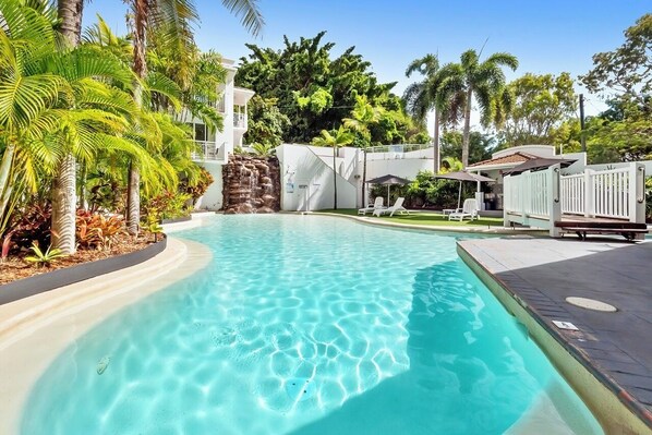 Relax by the serene pool surrounded by lush tropical vegetation and a soothing waterfall.