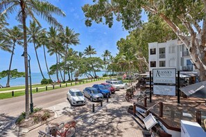 Enjoy stunning ocean views from this beachfront property, surrounded by lush palm trees and a paved walkway.