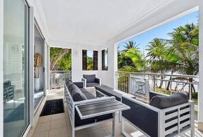 Enjoy the serene tropical views from this outdoor living space, featuring a sofa set and table on the balcony.