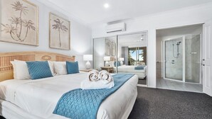 A hotel room with a large bed, a shower area, and a view of the outdoors. - 2 Bedroom Alassio Beach Front Apartment (Palm Cove)