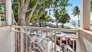 Un balcón con vista a una playa, coches estacionados y un letrero que dice 'ALASSIO'.