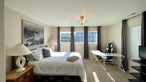 Une chambre d’hôtel avec un lit, un bureau, une chaise, une télévision et une grande fenêtre.