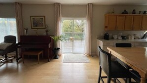Un salon spacieux avec un piano, une table à manger et un coin cuisine doté de meubles en bois.