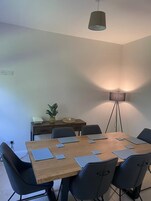 A conference room with a wooden table, six chairs, a floor lamp, and a potted plant.