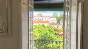 A balcony with a view of a lush garden and buildings in the background. - Cozy Studio in Marbella Old Town, Steps from Beach & Historic Sights (Marbella)