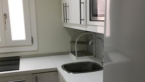A modern kitchen with a stainless steel sink, white cabinets, and a built-in microwave. - Cozy Studio in Marbella Old Town, Steps from Beach & Historic Sights (Marbella)