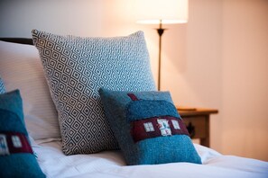 A bed with patterned pillows and a small house-shaped pillow. - An Cala Beag Self Catering apartment on The Waternish Peninsula   (Waternish Isle Of Skye)