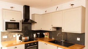 A modern kitchen with white cabinets, a black stove, a microwave, and a sink.