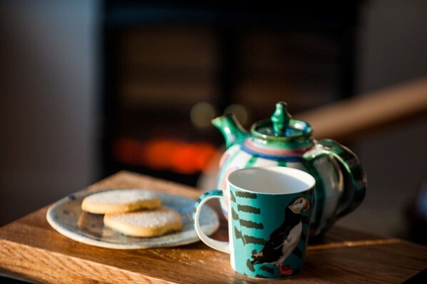 A teapot and mug on a wooden table with cookies. - An Cala Beag Self Catering apartment on The Waternish Peninsula (Waternish Isle Of Skye)