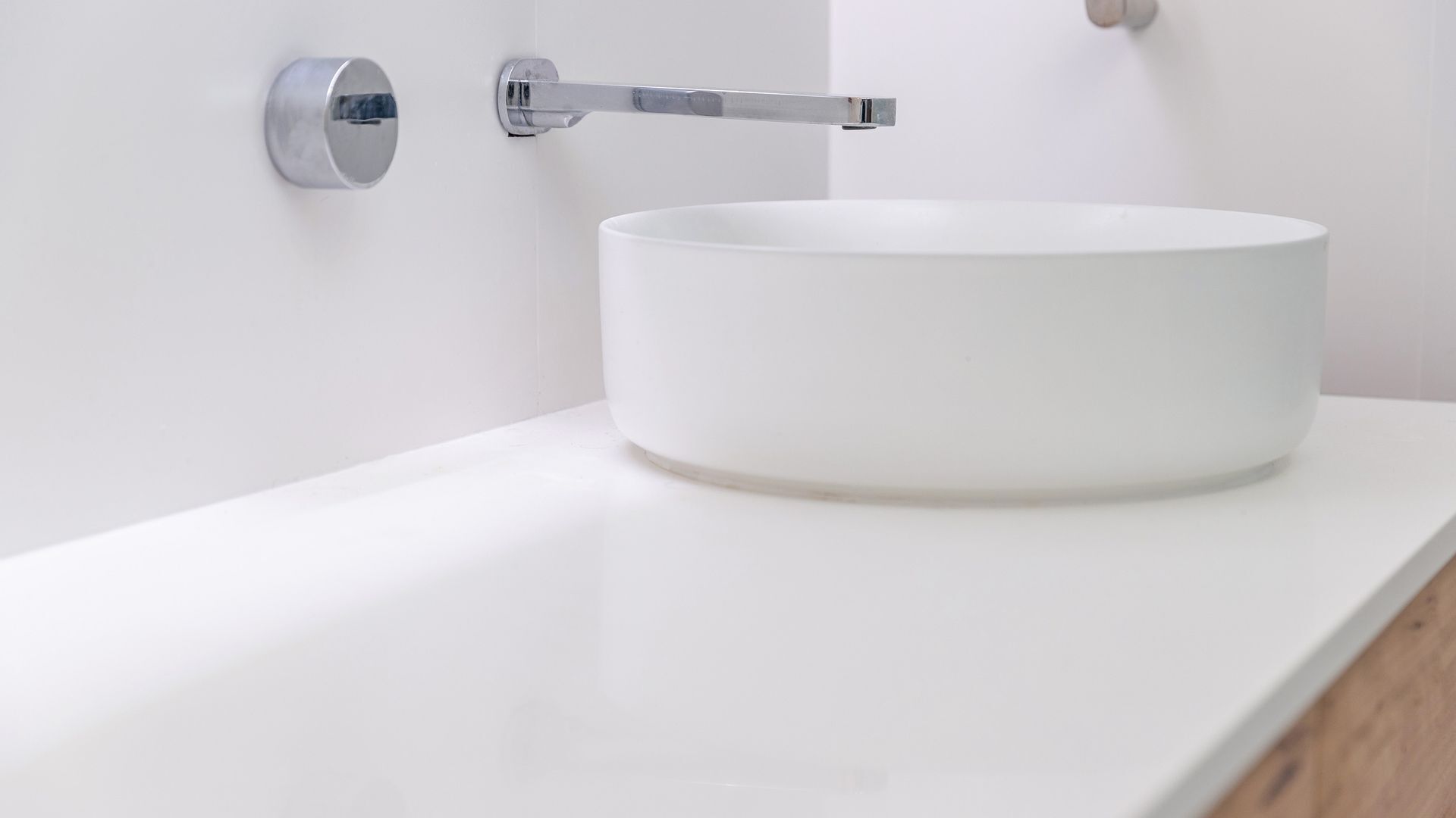 A white bathroom sink with a chrome faucet mounted on a white wall.