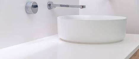 A white bathroom sink with a chrome faucet mounted on a white wall.