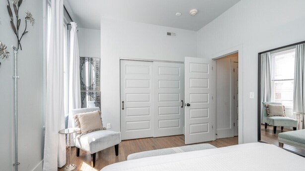 Une chambre à coucher avec un grand lit, une chaise, une petite table et une armoire.