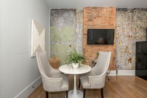 A dining area with two chairs, a small round table, and a potted plant.