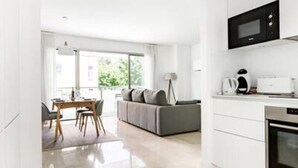 Une cuisine moderne avec des meubles blancs, un four à micro-ondes encastré et une machine à café.