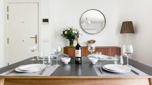 Un coin repas avec une table en bois dressée pour quatre personnes, un miroir au mur et une lampe.