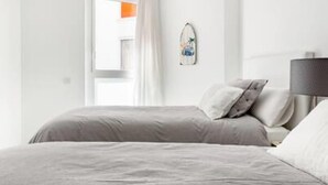 Une chambre à coucher moderne avec un lit, des oreillers, une table de chevet et une lampe fixée au mur.