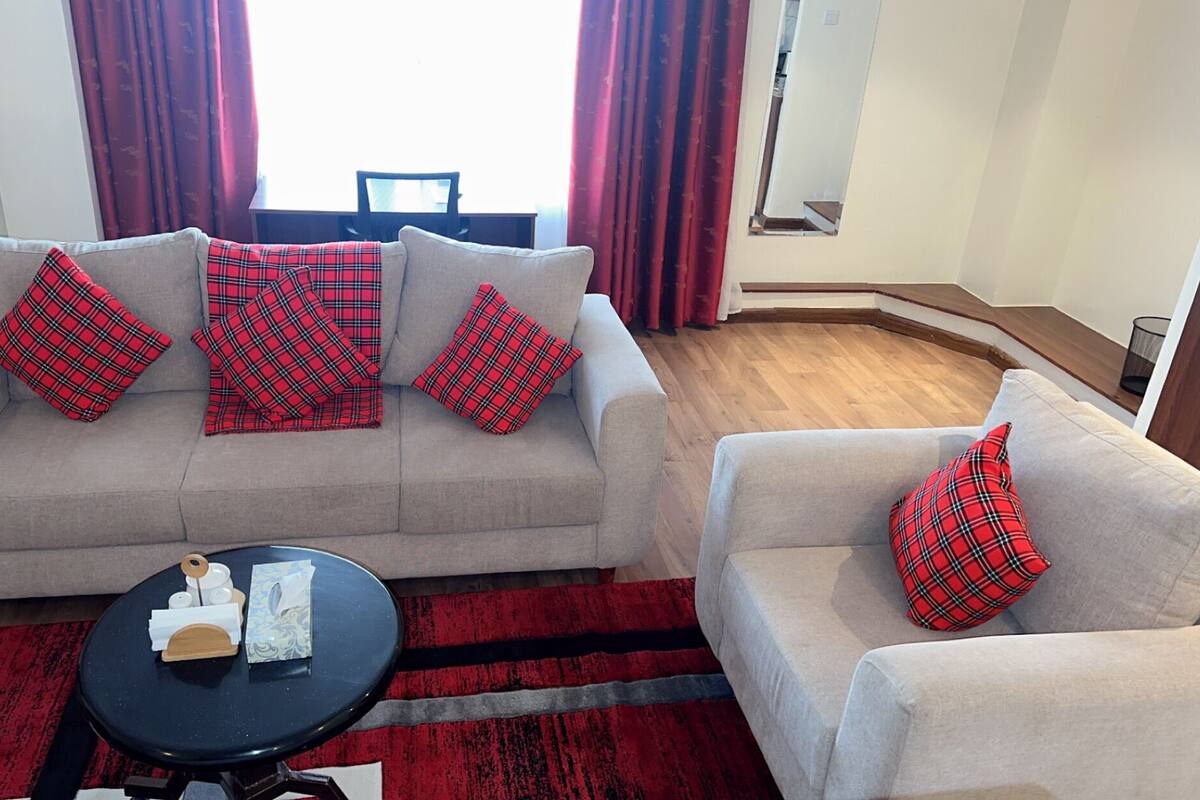 Una sala de estar con un conjunto de sofá, una mesa de centro y un cojín rojo a cuadros.