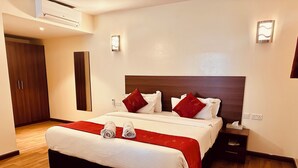 Een hotelkamer met een groot bed, twee nachtkastjes, een kast en een wandairconditioner.