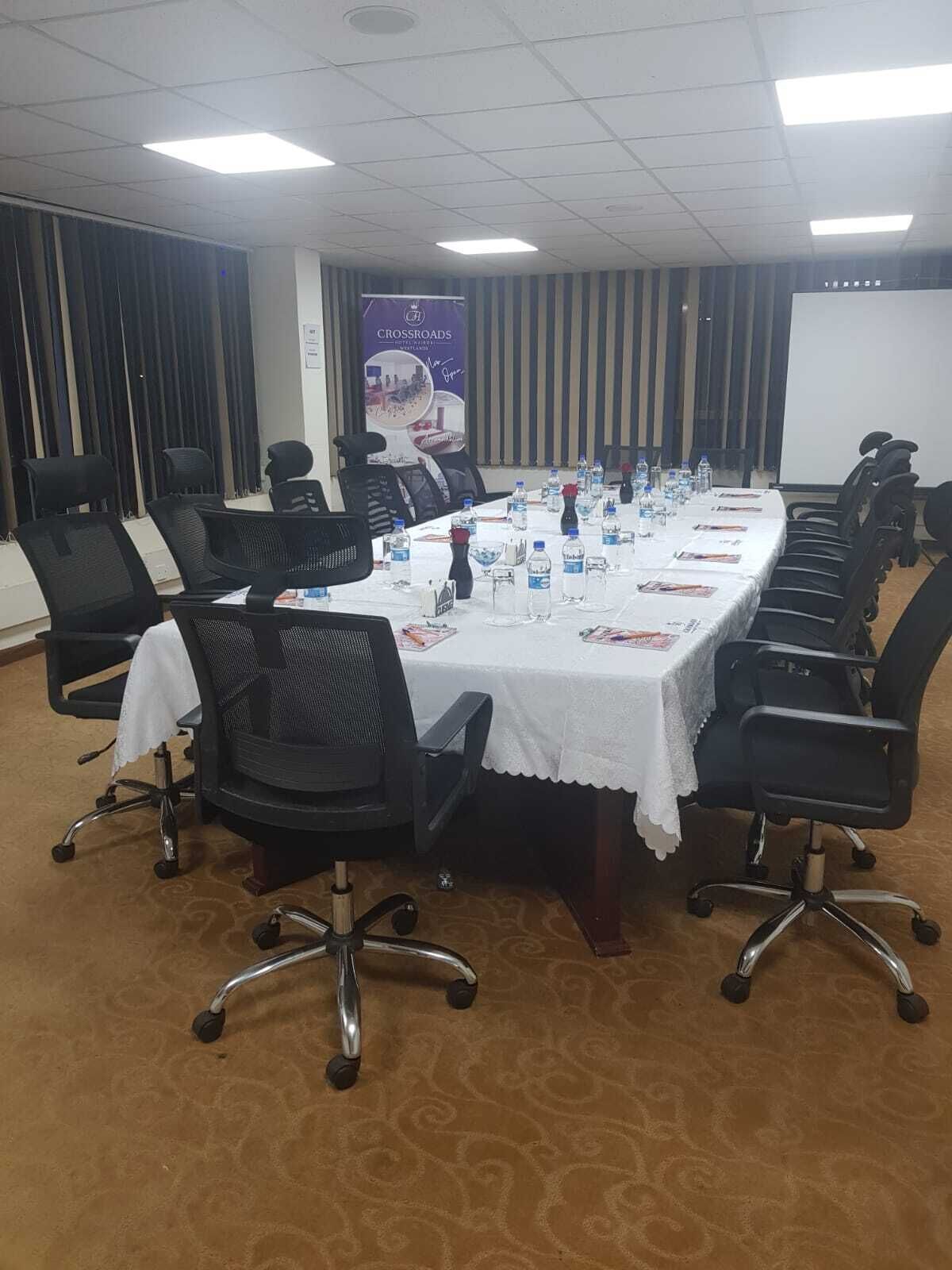 A conference room with a long table, black chairs, water bottles, and a banner on the wall.