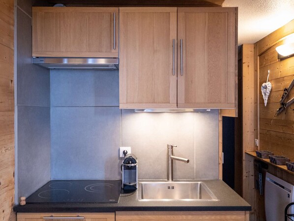 A compact kitchen with wooden cabinets, a stainless steel sink, and a built-in stovetop.