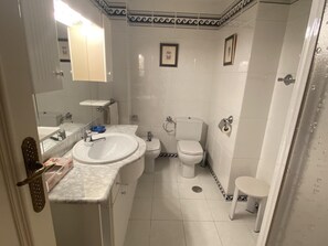 Et badeværelse med håndvask, toilet og brusebad.