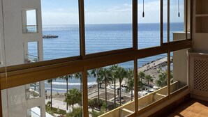 A room with large windows overlooking a beach and ocean.