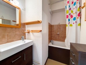 A bathroom with a white sink, wooden shelves, a shower, and a colorful shower curtain. - Cozy studio at the foot of the slopes with balcony (Les Menuires)