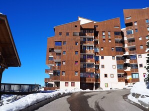 A multi-story building with balconies, a ski lift in the background, and snow on the ground. - Cozy studio at the foot of the slopes with balcony (Les Menuires)