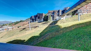 A modern building complex with multiple residential units, situated on a hillside with a clear view of the surrounding landscape.