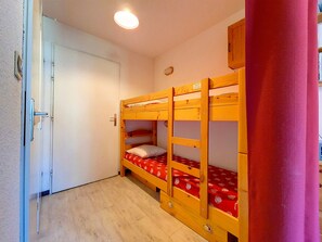 A room with a bunk bed, a door, and a small cabinet. - Cozy studio at the foot of the slopes with balcony (Les Menuires)