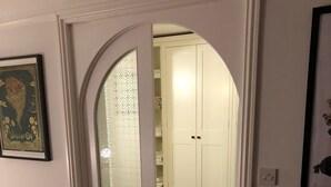 Ein Flur mit einer weißen Tür, die zu einem Raum mit einem weißen Kleiderschrank und einer Heizung führt.