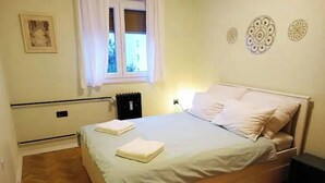 Une chambre à coucher avec un lit, une fenêtre, un radiateur et un élément décoratif mural.