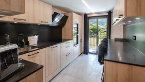 Een moderne keuken met houten kastjes, een zwart aanrecht en een inbouwoven.