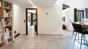 Een modern interieur met een keuken, een eethoek met barstoelen en een boekenplank.