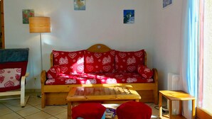 Ein gemütliches Wohnzimmer mit einer Holzsofa, einem kleinen Tisch und einer Lampe.