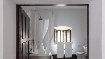 Une salle de bain avec une baignoire sur pieds, un rideau de douche et des toilettes.