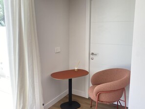 A corner room with a white door, a small round table with a candle, and a pink chair. - Sunny Apartment in Marbella: 2nd Line Beach, Terrace, Fiber, A/C, Pools, 24/7 Reception (Marbella)