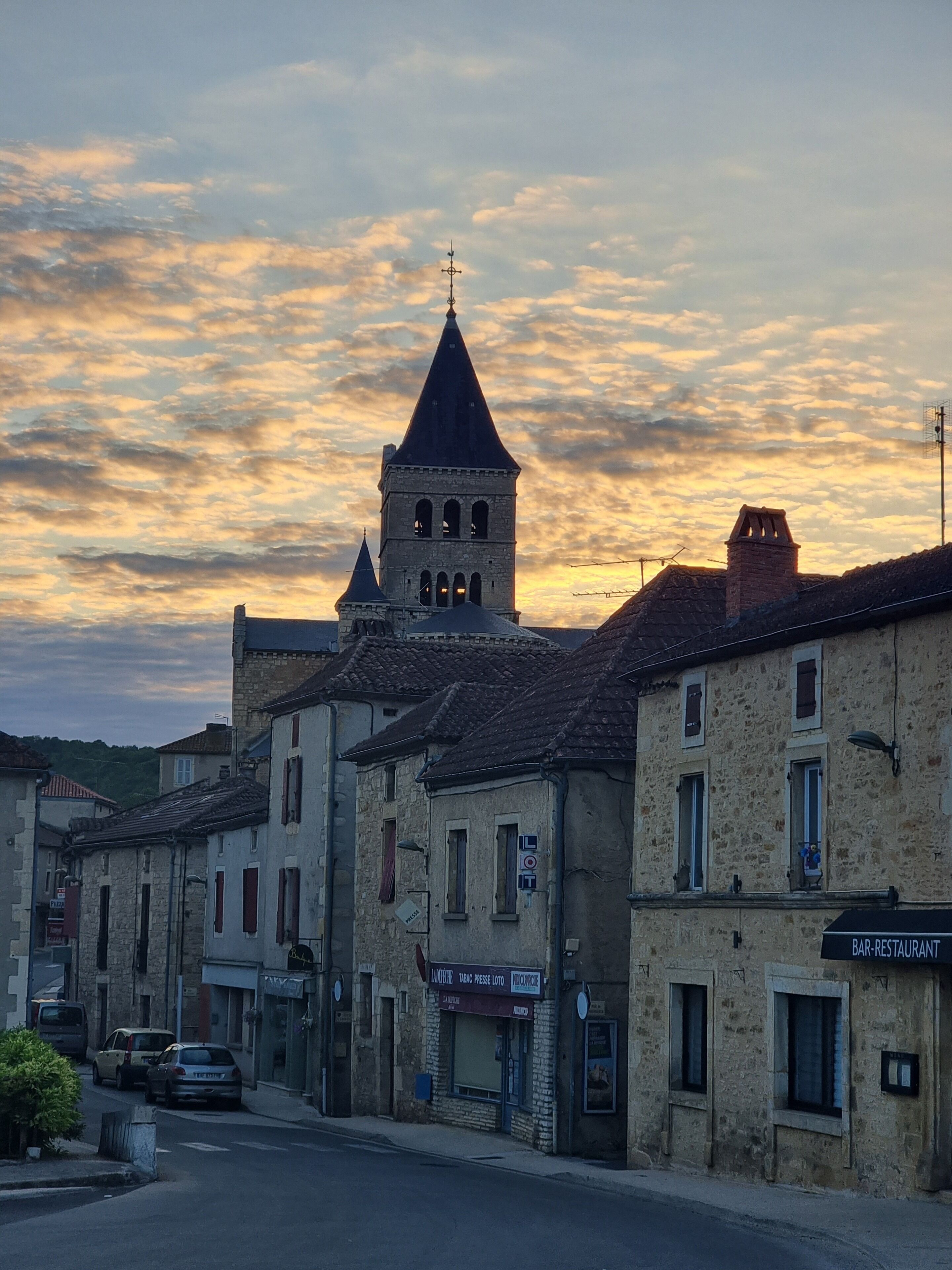A historic town with stone buildings, a prominent church tower, and a bar-restaurant.