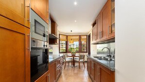 Une cuisine moderne dotée de meubles en bois, d’appareils électroménagers en acier inoxydable et d’un coin repas avec une table et des chaises.