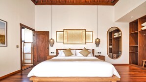 A spacious bedroom with a large bed, wooden flooring, a wooden ceiling, a wardrobe, and a bedside table with lamps. - Villa Kalita (Seminyak)